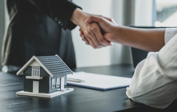 Home model. Real estate agents and buyers handshake after signing a business contract, renting, buying, mortgage, loan or home insurance